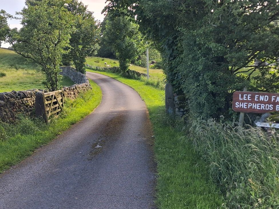 A gravel road with trees and a sign at Shepherd's Barn in Lancaster