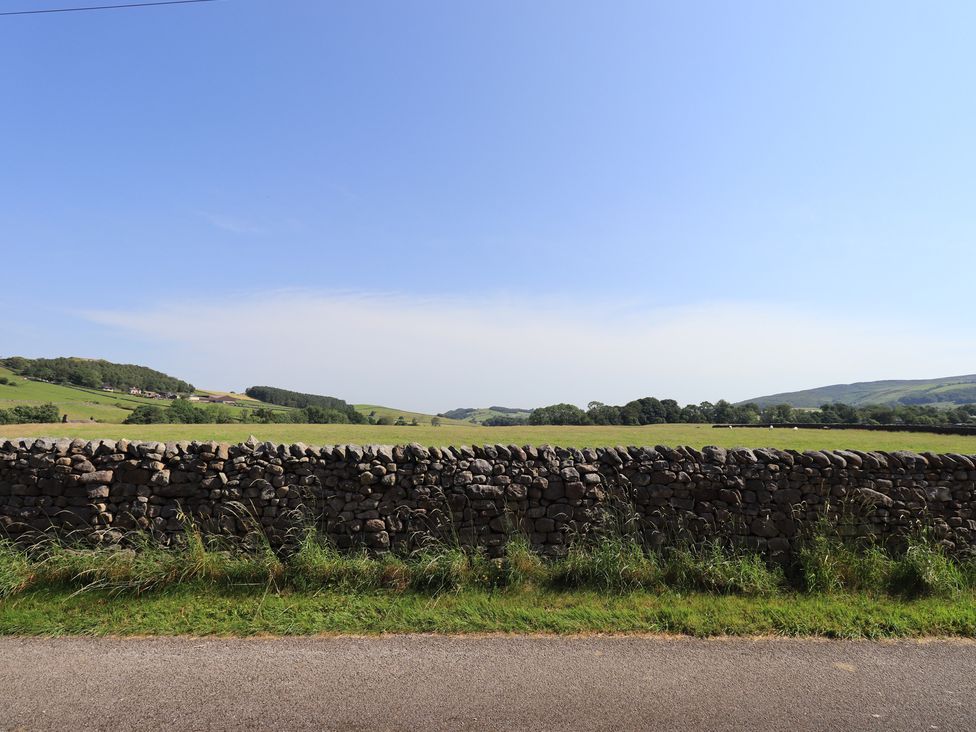 A stone wall with a field and road at Shepherd's Barn in Lancaster