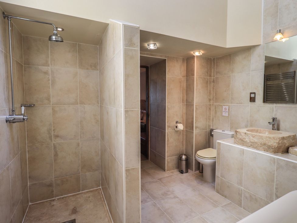 A bathroom with shower, toilet, and stone sink at Shepherd's Barn, Lancaster