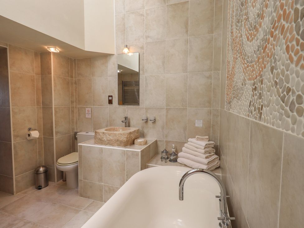 A bathroom with a bathtub, a toilet, and a stone sink at Shepherd's Barn in Lancaster