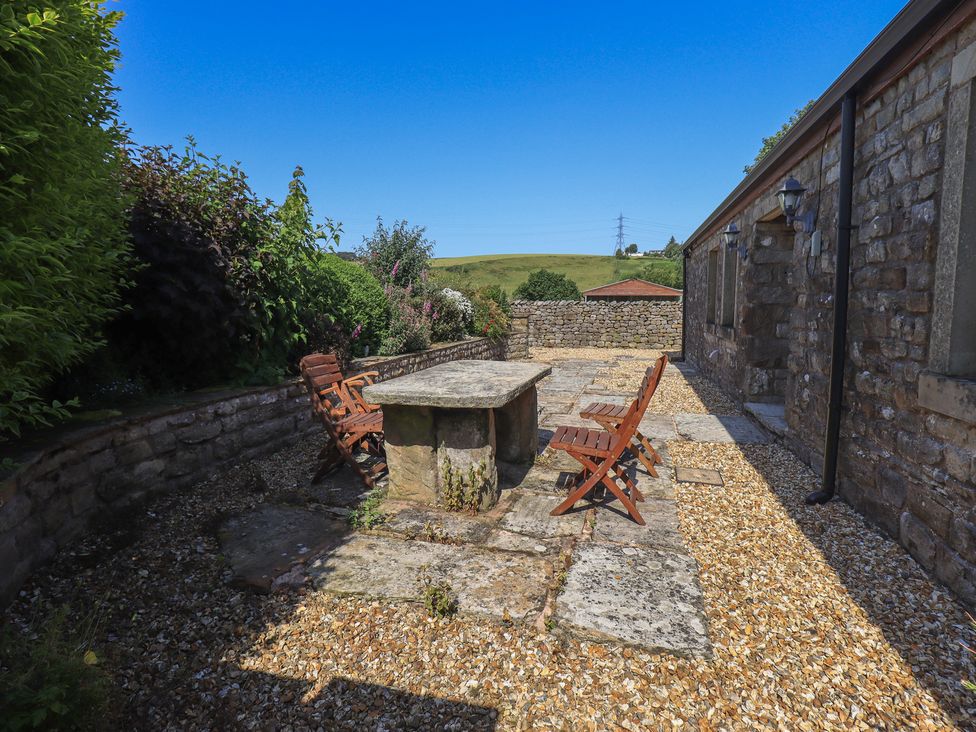 An outdoor patio with a stone table and wooden chairs at Shepherd's Barn in Lancaster