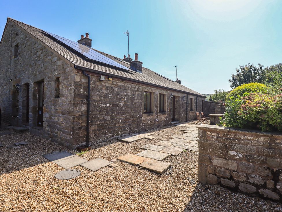 An outdoor view of a stone building with solar panels and a gravel pathway at Shepherd's Barn Lancaster