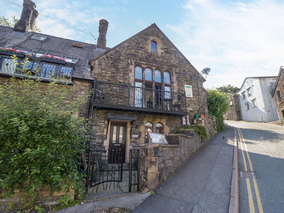 A stone building with a balcony and door at Hillside Cottage in Bowness-On-Windermere