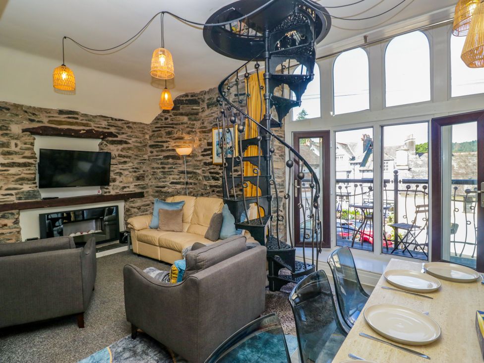 A living room with a sofa and spiral staircase at Hillside Cottage Bowness-On-Windermere