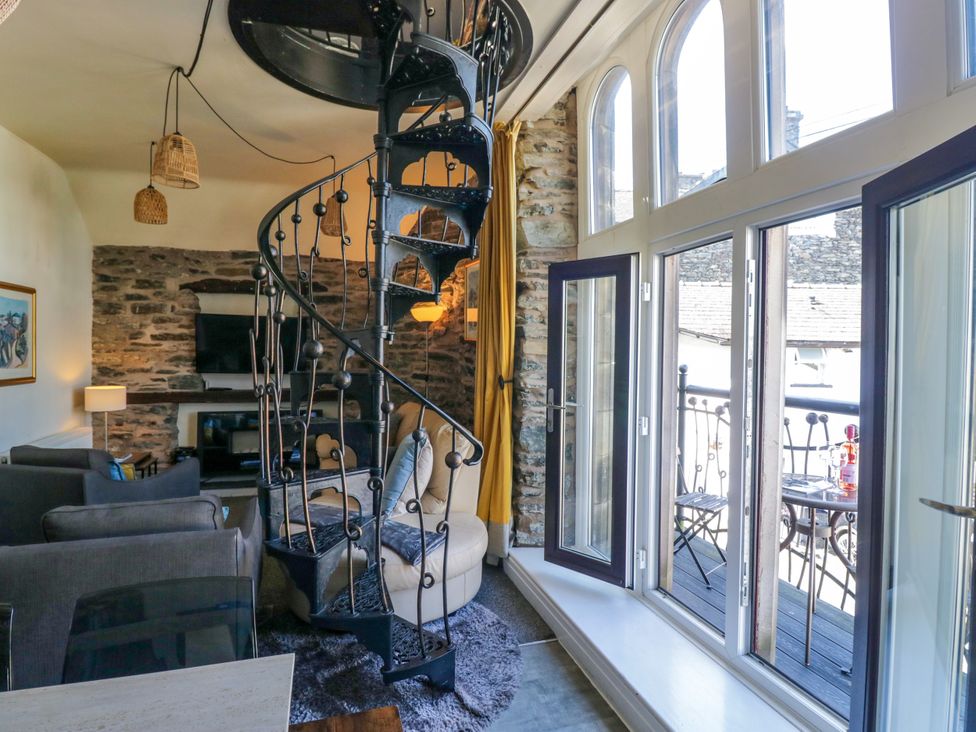 A living room with a spiral staircase and sofa at Hillside Cottage in Bowness-On-Windermere