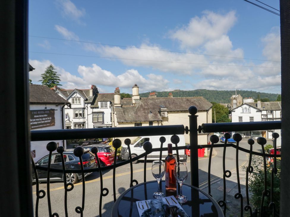 A balcony view with a table and glasses at Hillside Cottage in Bowness-On-Windermere