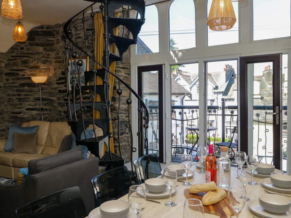 A dining room with a spiral staircase and a dining table at Hillside Cottage in Bowness-On-Windermere
