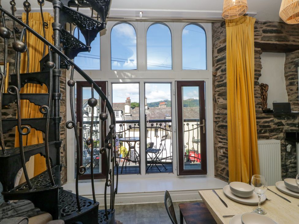 A dining room with a spiral staircase and table at Hillside Cottage Bowness-On-Windermere
