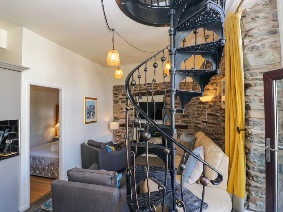 A living room with spiral staircase and seating area at Hillside Cottage in Bowness-On-Windermere