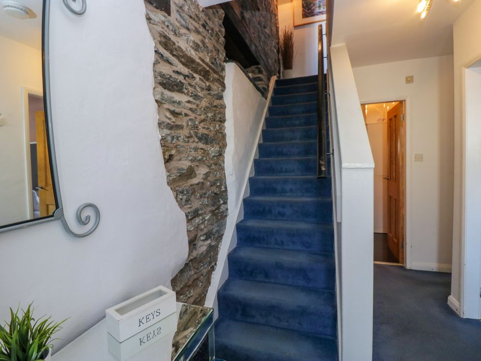 A hallway with a staircase and mirror at Hillside Cottage in Bowness-On-Windermere