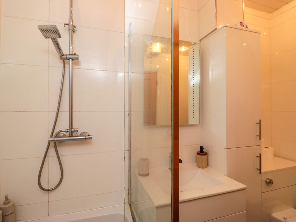 A bathroom with a shower, sink, mirror, and toilet at Hillside Cottage Bowness-On-Windermere