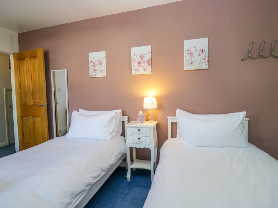 A bedroom with two beds and a bedside table at Hillside Cottage in Bowness-On-Windermere