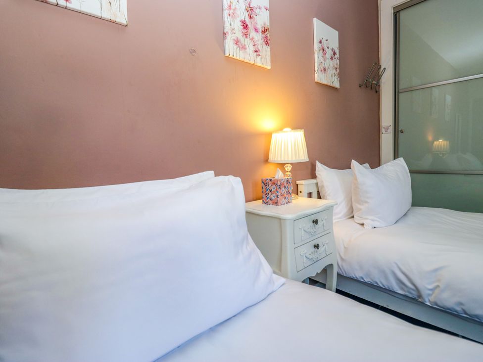 A bedroom with two beds and a nightstand at Hillside Cottage in Bowness-On-Windermere