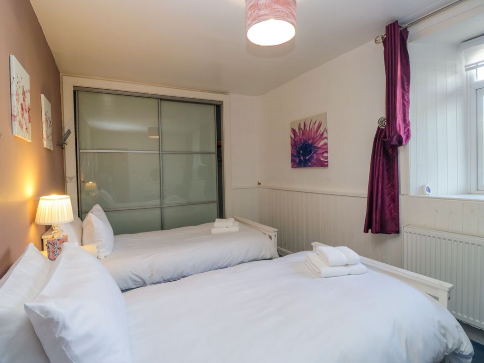 A bedroom with two beds and a sliding door at Hillside Cottage Bowness-On-Windermere