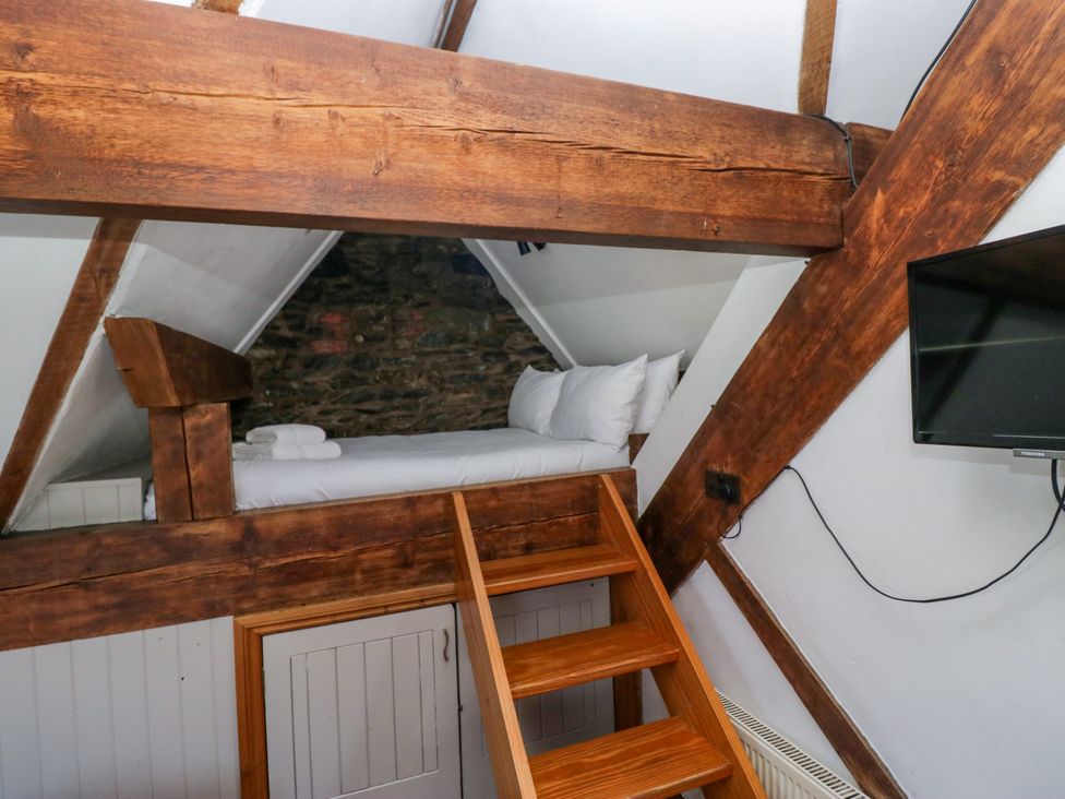 A loft with a bed and stairs at Hillside Cottage in Bowness-On-Windermere
