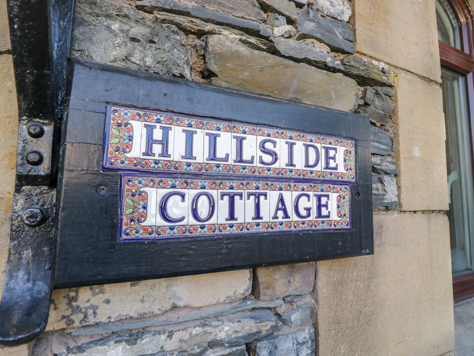 A sign displaying 'Hillside Cottage' on a stone wall at Hillside Cottage in Bowness-On-Windermere