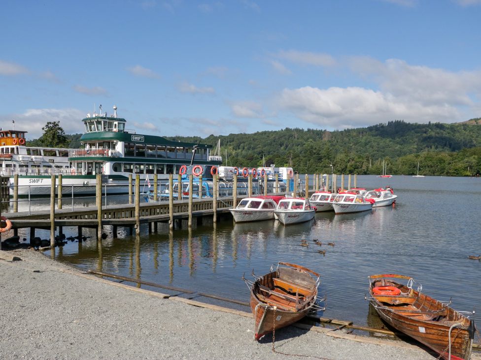 A pier with boats and a ferry on water at Hillside Cottage in Bowness-On-Windermere