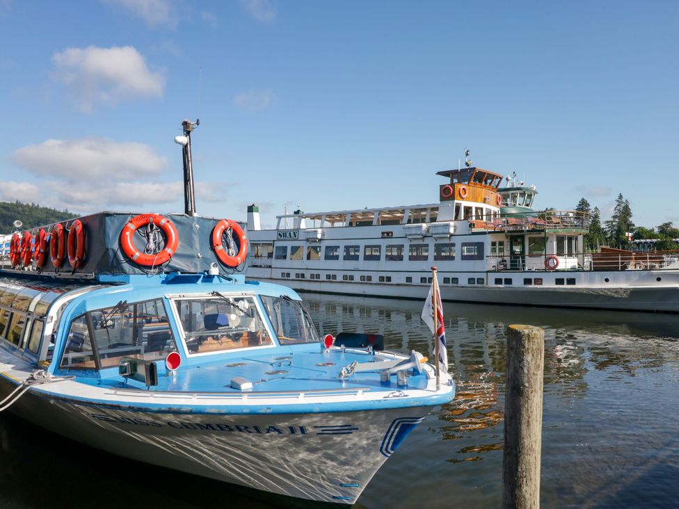 Two boats docked at a river at Hillside Cottage in Bowness-On-Windermere