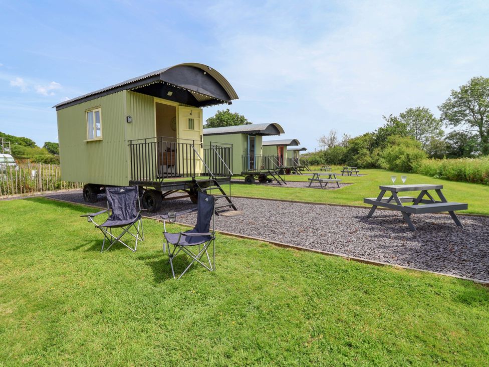 Huts with picnic tables and chairs at Bee Happy Whitchurch