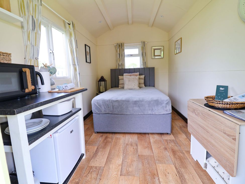 A bedroom with a bed and a microwave at Bee Happy in Whitchurch