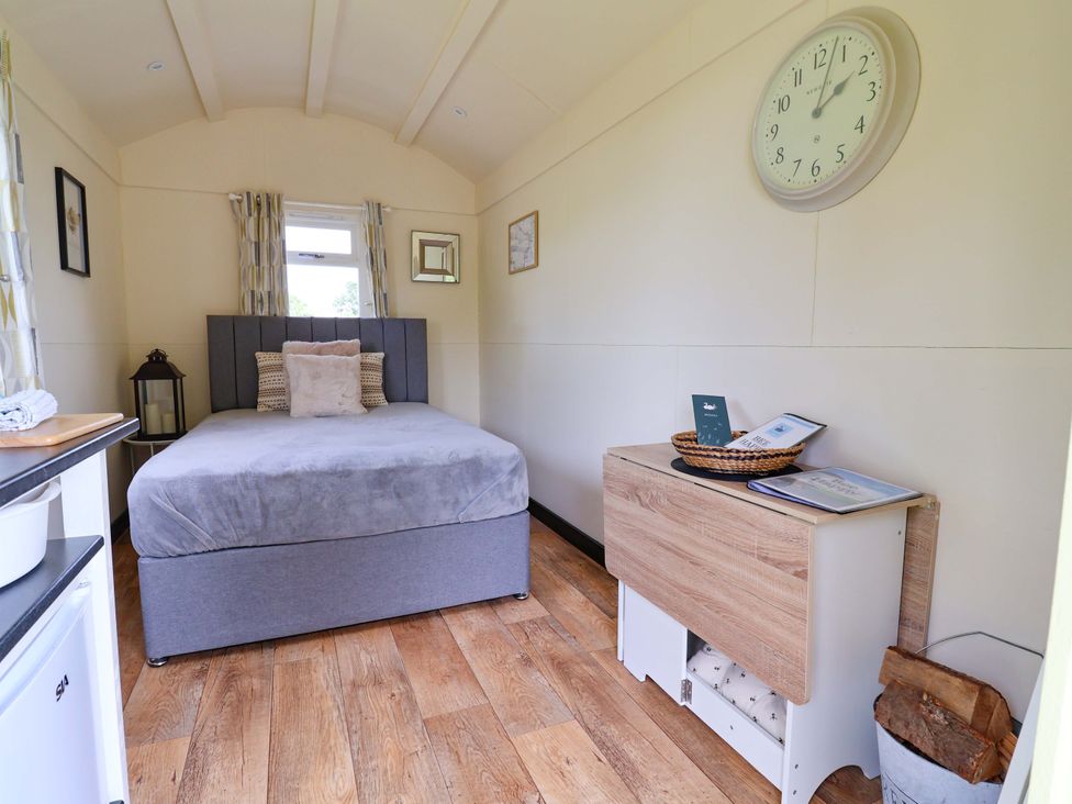 A bedroom with a bed and wooden drawer unit at Bee Happy in Whitchurch