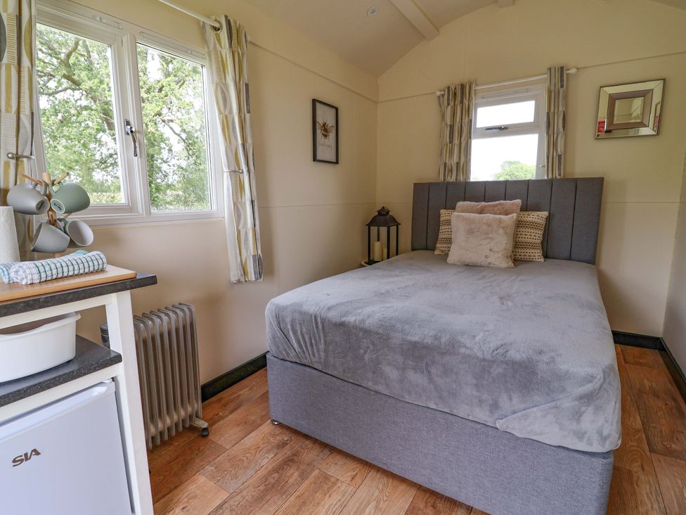 A bedroom with a bed and windows at Bee Happy in Whitchurch