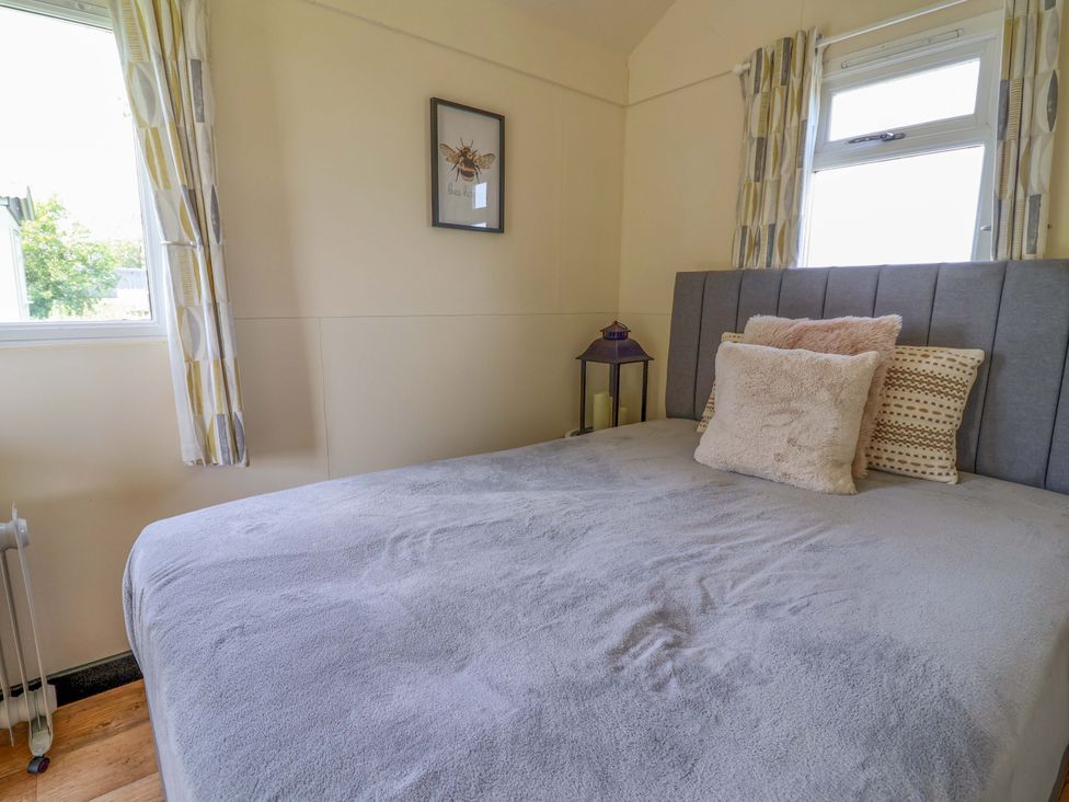 A bedroom with a bed and bedside table at Bee Happy in Whitchurch