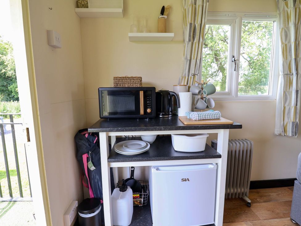 A kitchen area with a microwave and kettle at Bee Happy in Whitchurch