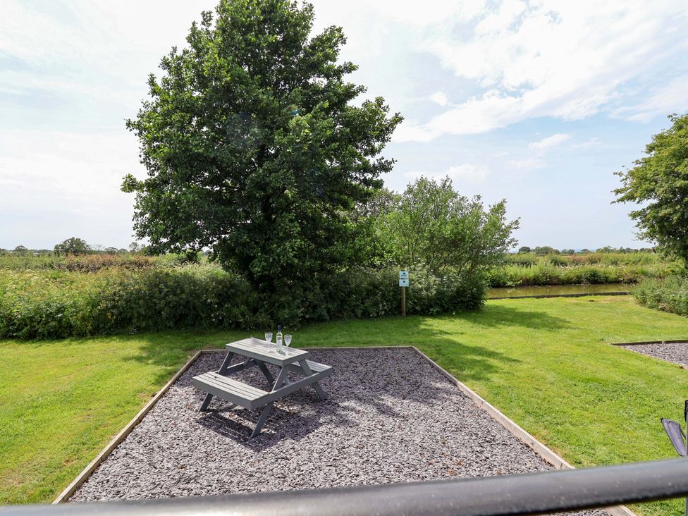 A picnic table with glasses in a garden at Bee Happy in Whitchurch