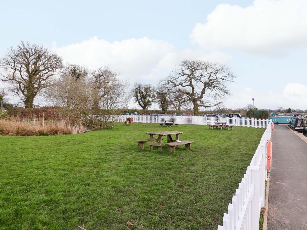 A garden with picnic tables and trees at Bee Happy in Whitchurch