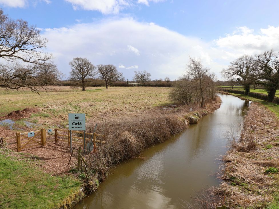 An outdoor area with a café sign and a waterway at Bee Happy in Whitchurch