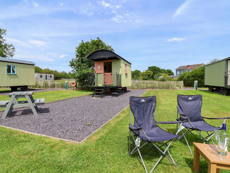 An outdoor area with caravans and seating at Foxes Den in Whitchurch