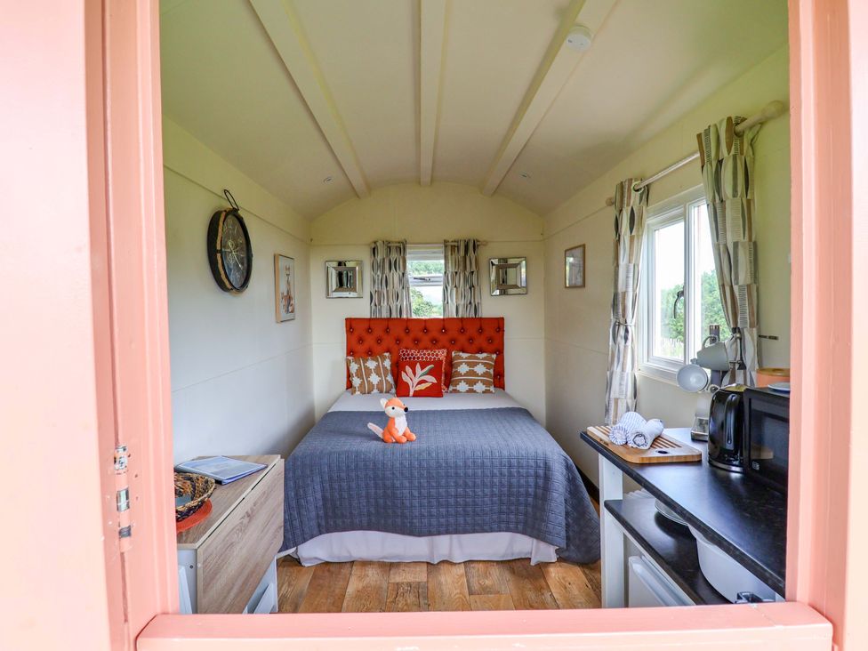 A bedroom with a bed and kitchenette at Foxes Den Whitchurch