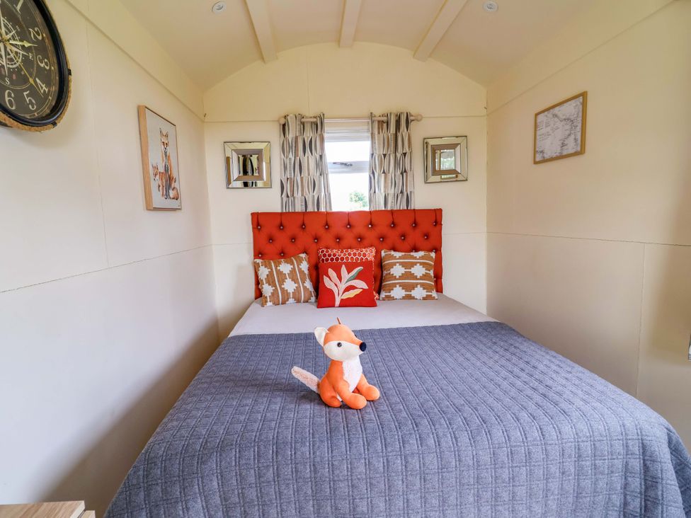 A bedroom with a bed and clock at Foxes Den in Whitchurch