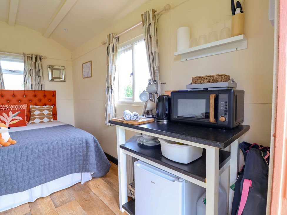A bedroom with a bed and kitchen area at Foxes Den Whitchurch