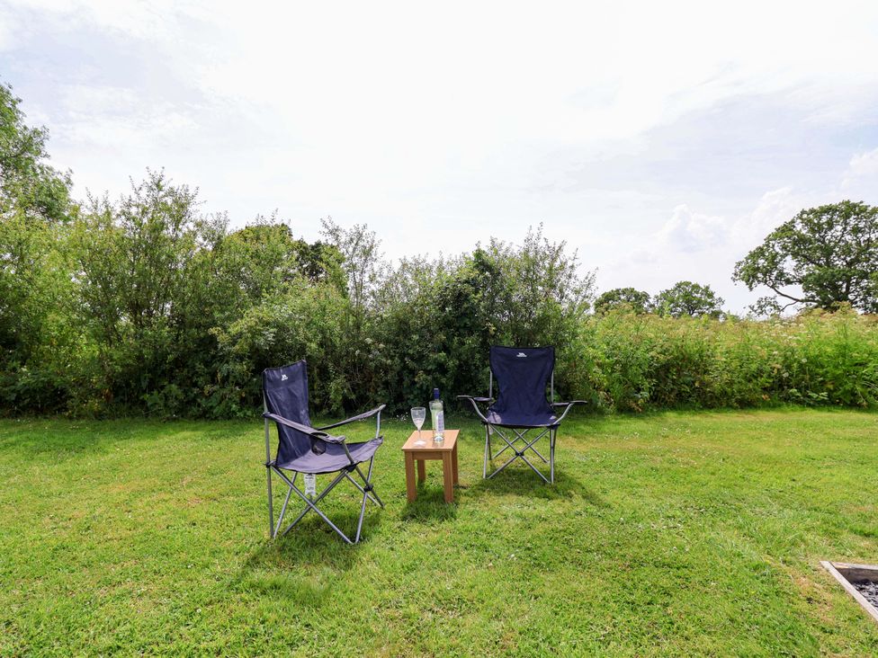 Two camping chairs and a table with drinks in the garden at Foxes Den Whitchurch