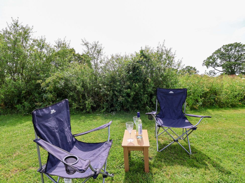 Two camping chairs and a table with drinks outside at Foxes Den in Whitchurch