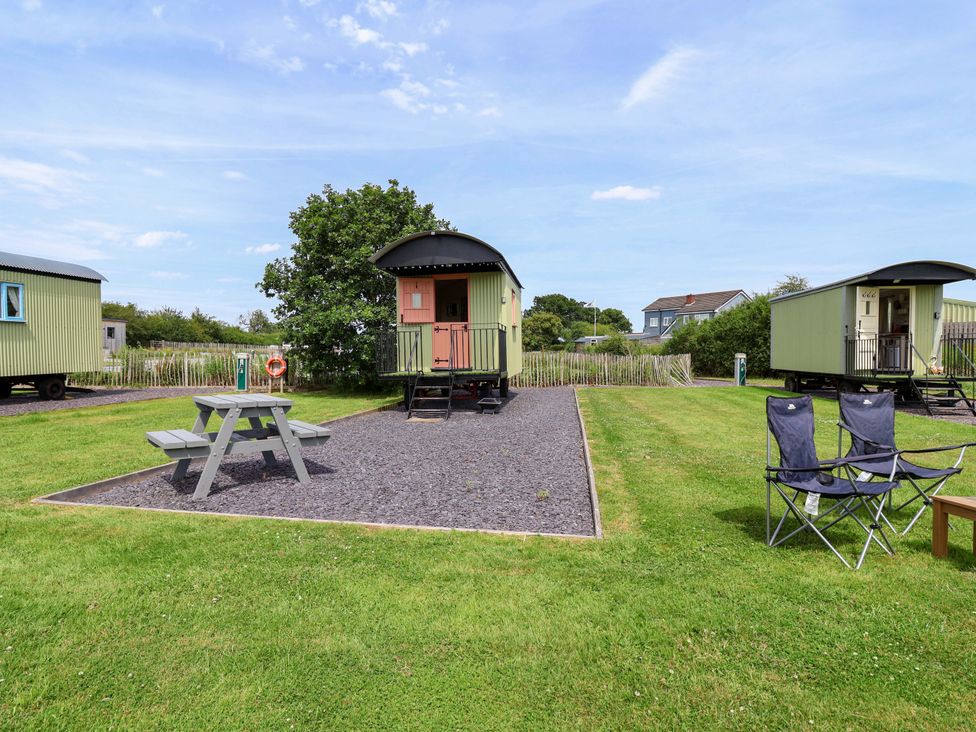 An outdoor area with shepherd huts and seating at Foxes Den in Whitchurch