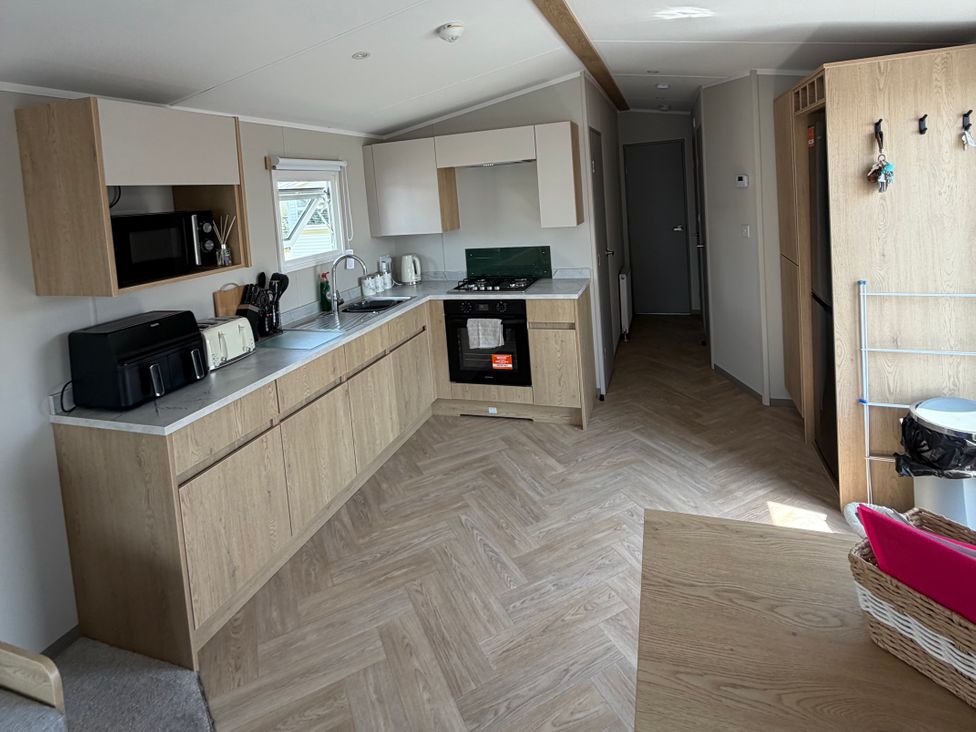 A kitchen with a stove, microwave, and sink at Trecco bay holiday park- Magnolia 11, Porthcawl