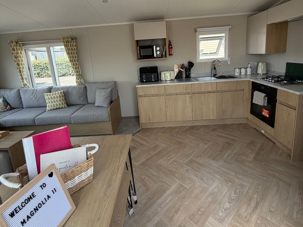 A living room and kitchen area with a sofa and kitchen appliances at Trecco bay holiday park- Magnolia 11, Porthcawl