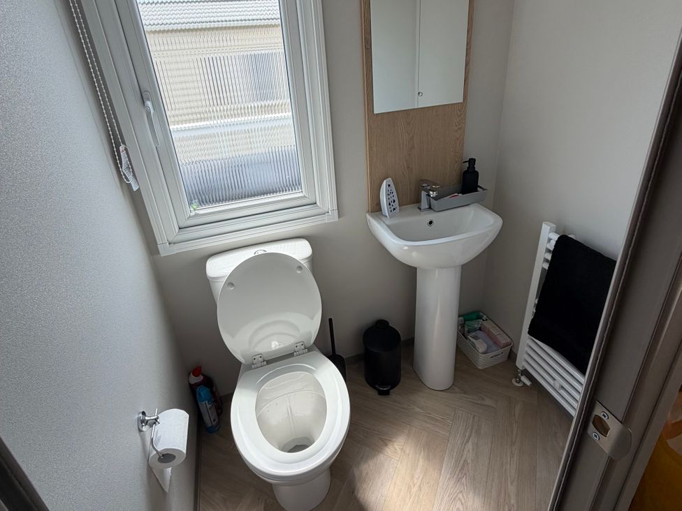 A bathroom with a toilet, sink, and towel radiator at Trecco bay holiday park- Magnolia 11 in Porthcawl