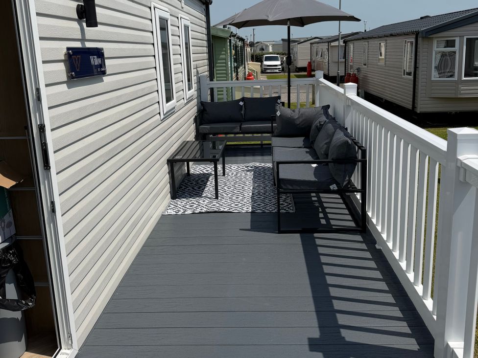 An outdoor patio with a sofa, table, and umbrella at Trecco bay holiday park- Magnolia 11 Porthcawl