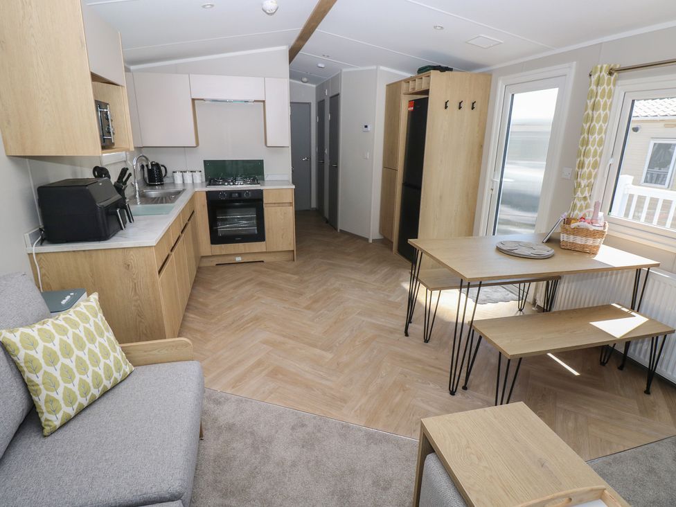 A kitchen with a stove and dining table at Trecco Bay Holiday Park - Magnolia 11, Porthcawl