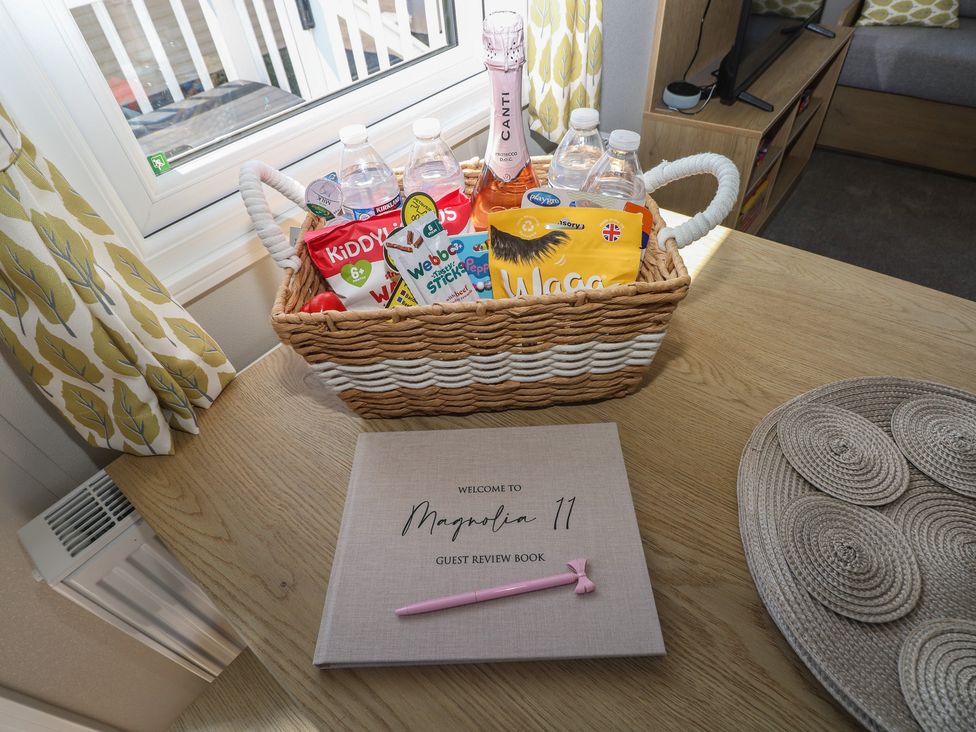 A living room with a basket of snacks and water bottles at Trecco Bay Holiday Park - Magnolia 11 Porthcawl