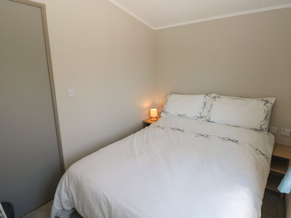 A bedroom with a bed and nightstand at Trecco Bay Holiday Park - Magnolia 11, Porthcawl