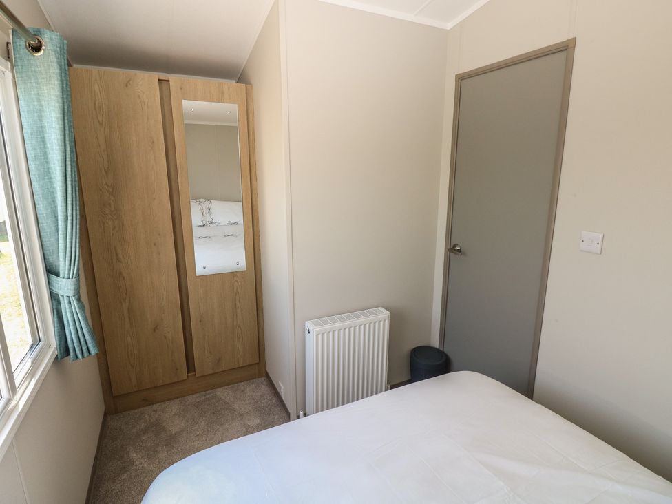 A bedroom with a bed, wardrobe, and radiator at Trecco Bay Holiday Park - Magnolia 11, Porthcawl