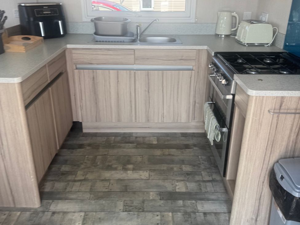 A kitchen with a stove, sink, and cabinets at Trecco Bay in Porthcawl