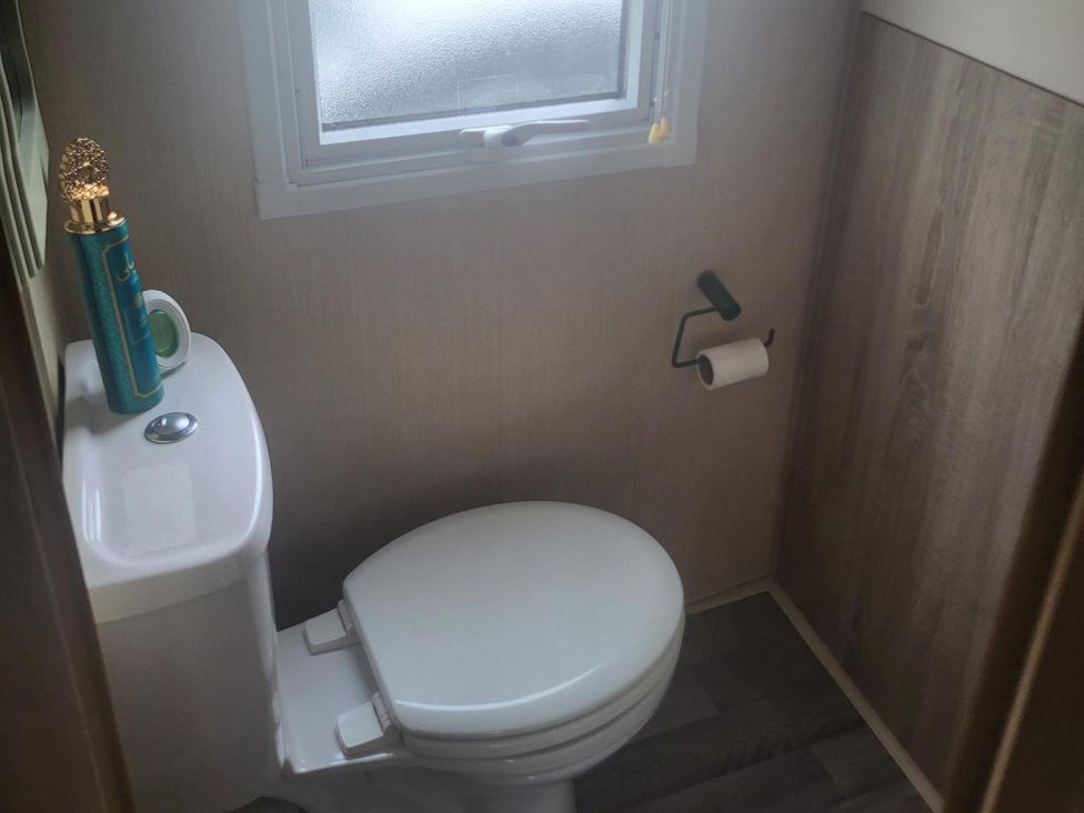 A bathroom with a toilet and window at 164 Broadland Sands Holiday Park, Lowestoft