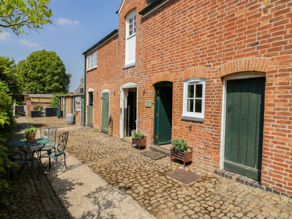 An outdoor area with a cobblestone pathway and green doors at The Stable Flat
