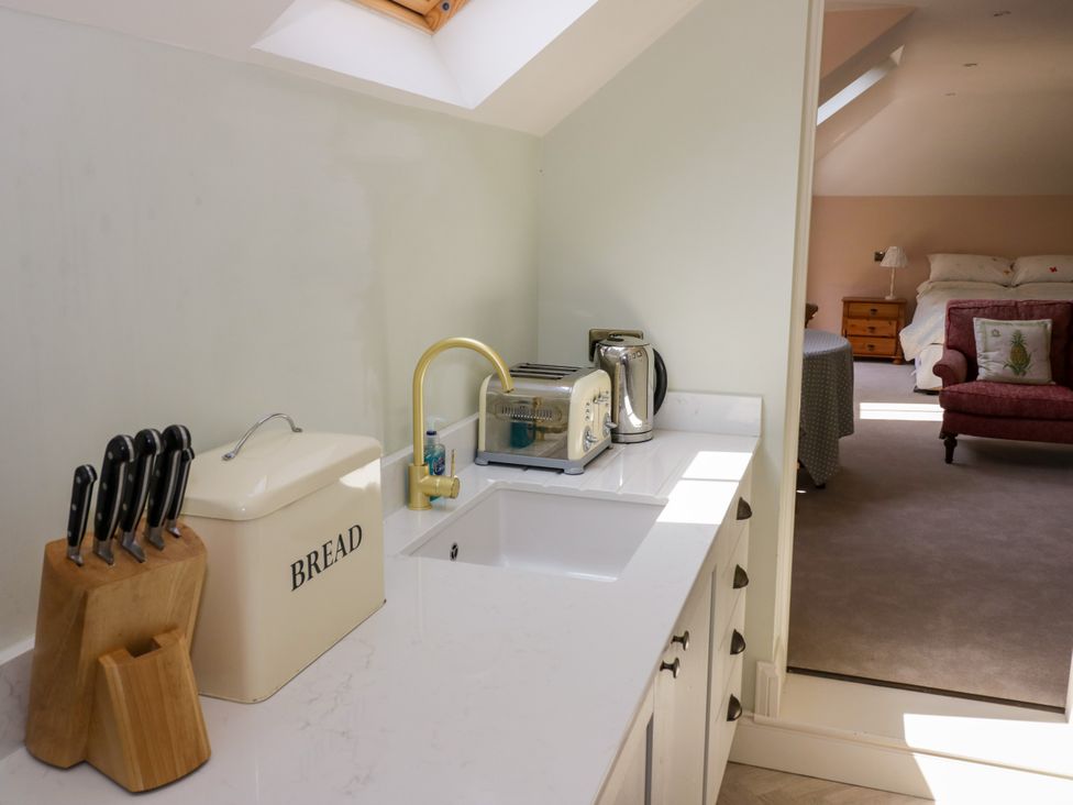A kitchen with a sink, kettle, toaster, knife block, and bread box at The Stable Flat in 